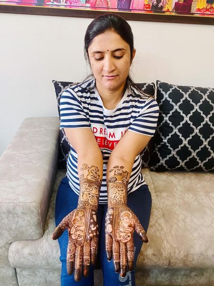 A proud mom-to-be showing off her full-arm maternity mehndi. The design is filled with traditional patterns and symbols of new life and happiness.