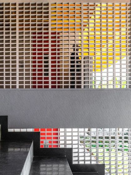 A custom-designed breeze block screen at L'Atelier creates a porous partition, allowing for visual connection and the play of light and shadow. The design adds a layer of texture and geometric interest to the interior.