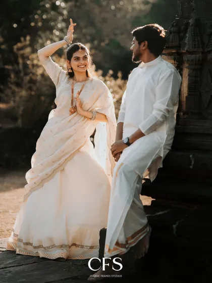 A playful, candid moment during a traditional shoot. Her joyful dance and his smiling gaze create a lively and heartwarming image.