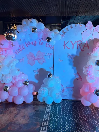 The full view of the 'Half Way to One' celebration, with two arched backdrops and beautiful pink and white balloon garlands accented with silver.