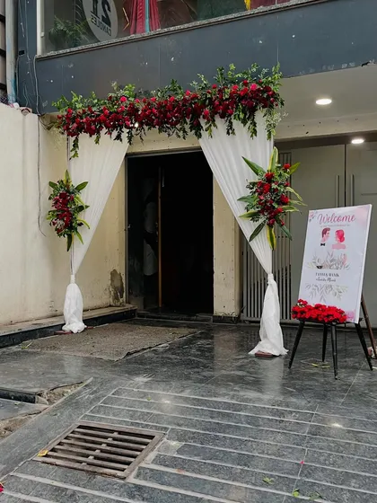 A simple yet elegant entrance arch I created for a Roka ceremony. The white drapes are accented with rich red floral bouquets and a personalized welcome sign for the couple.