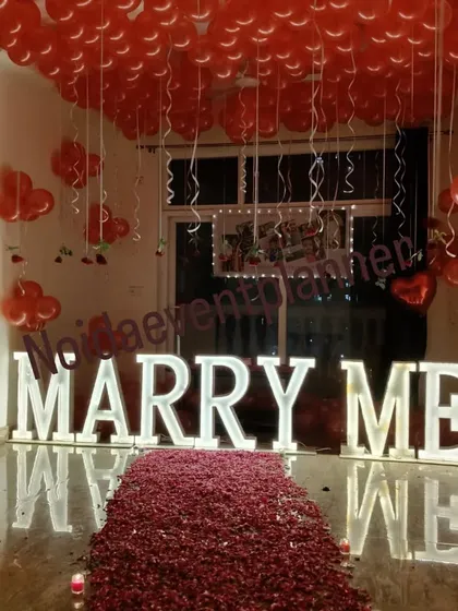 The glossy floor reflects the glowing 'MARRY ME' letters, adding an extra layer of magic to this romantic proposal setting.