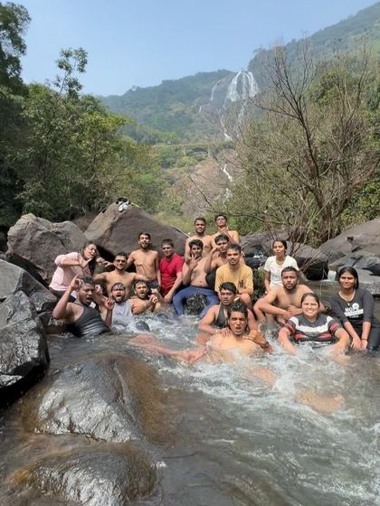 Another angle of our group enjoying the cool waters at Dudhsagar, with the falls in the background.