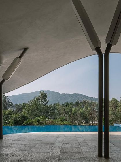 A detail of the tree-like structural columns supporting the sweeping parametric roof. This perspective highlights how the architecture frames a perfect, uninterrupted view of the pool and the lush green hills in the distance.