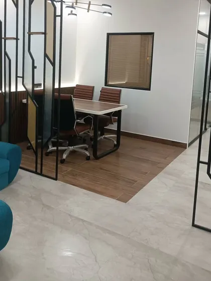 The completed meeting area in a CA office, showcasing the blend of different materials. The space features a custom metal partition, wooden flooring, and glass walls, creating a modern yet defined zone for discussions.