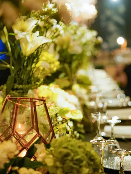 A close-up of the tablescape, with a geometric candle holder and fresh white and green florals creating a sophisticated and modern look.