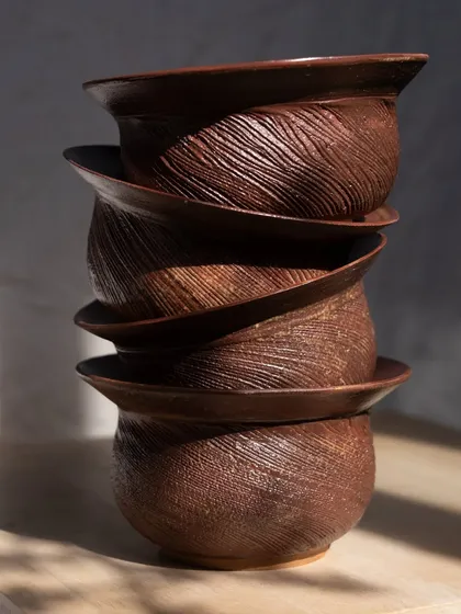 A stack of planters from 'The Dhora' Collection. The carved textures are reminiscent of shifting sands, creating a sense of movement and stillness.