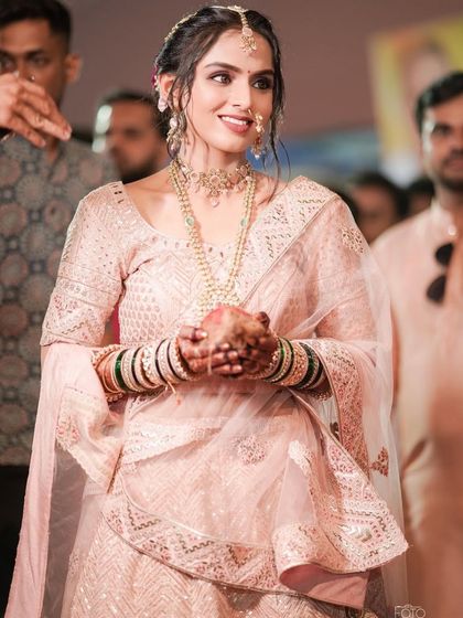 A beautiful moment from a Gujarati wedding ceremony. The bride's minimal makeup in pastel pink tones looks serene and elegant.
