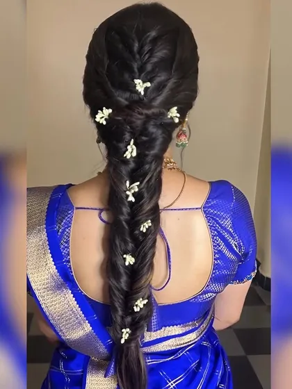 A detailed shot of a fishtail braid with small, delicate white flowers. This is a perfect hairstyle for a bride who wants a traditional yet fresh and modern look.