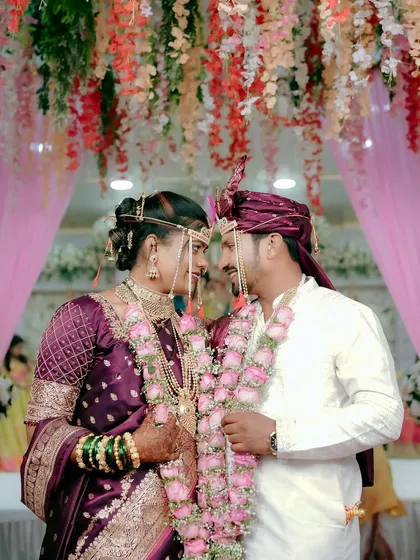 The couple gazes at each other under a canopy of flowers during their Maharashtrian wedding. This shot captures the romance and the beautiful decor of the venue.