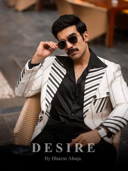 A close-up on the confident attitude this pinstripe blazer inspires. The aviator sunglasses and sharp tailoring combine for an iconic, gangster-chic aesthetic.