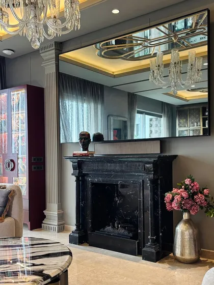 The same fireplace after completion, now a stunning centerpiece with a large mirror, flowers, and decor.