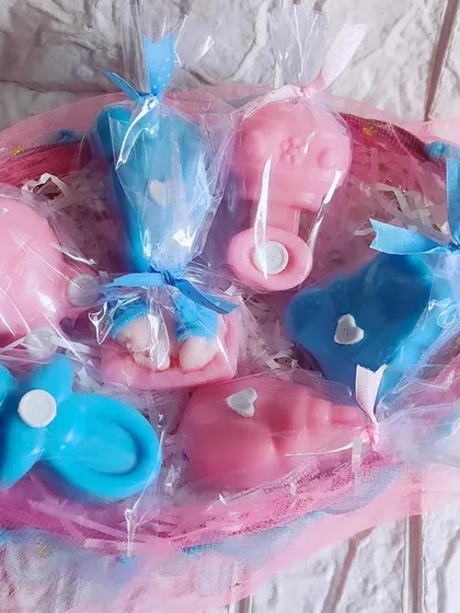 A basket of pink and blue baby shower themed soaps, including rattles, footprints, and sleeping babies.
