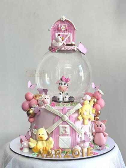 A straight-on view of the pink farm cake. You can see the detailed windmill and the variety of animals, each with its own personality.