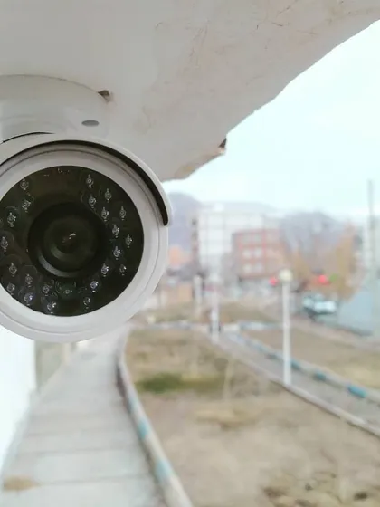 This dome camera is positioned to monitor a wide area, such as a parking lot or public space. Its discreet design and durable housing make it suitable for outdoor surveillance.