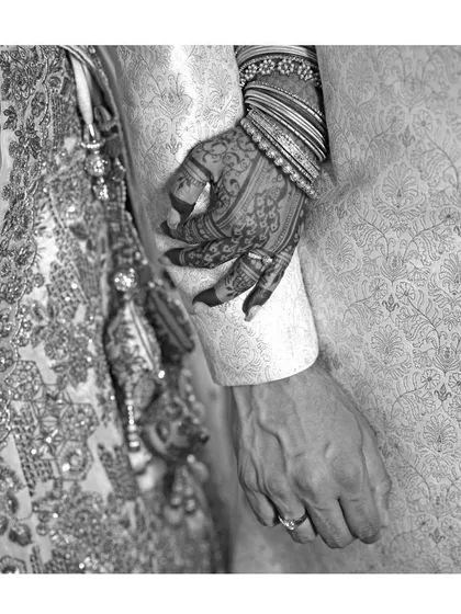 Another artistic black and white shot, focusing on the bride's hand on the groom's arm, showcasing the beauty of the stained henna.