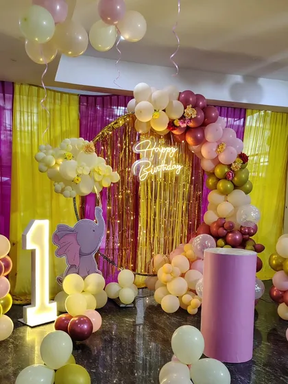 The main backdrop for the elephant-themed party, featuring a half-arch of balloons and a neon sign.
