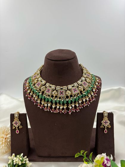 The Divya Premium Antique Gold Necklace set. This piece features unique square motifs with Meenakari work, layered with green and ruby beads for a colorful yet traditional look.