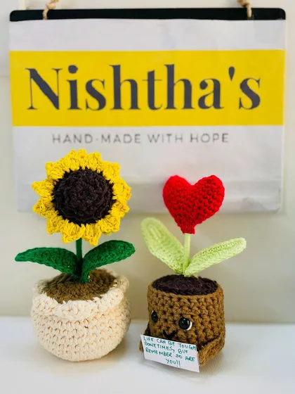 We call these our happy pots. On the left is a cheerful crochet sunflower, and on the right is a little heart pot holding a custom note. These small creations are perfect for your desk or as a thoughtful gift to brighten someone's day.