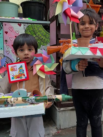 Two young friends showing off their handmade Holi platters and pichkaris.
