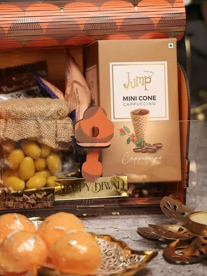 A wooden box with an acrylic lid, combining rustic and modern elements. This hamper includes a mix of sweets and savory snacks.