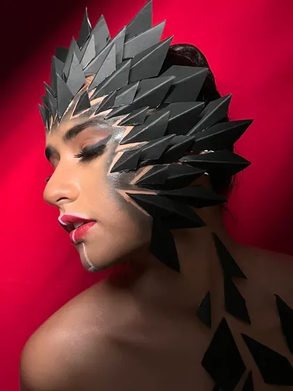 The use of dramatic lighting adds depth and dimension to the fantasy headpiece and makeup.