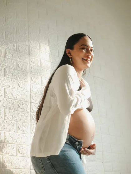 Sometimes the most beautiful portraits are the most relaxed. This casual maternity photo, with a simple white shirt and jeans, captures a moment of pure, unposed happiness and the natural glow of pregnancy.