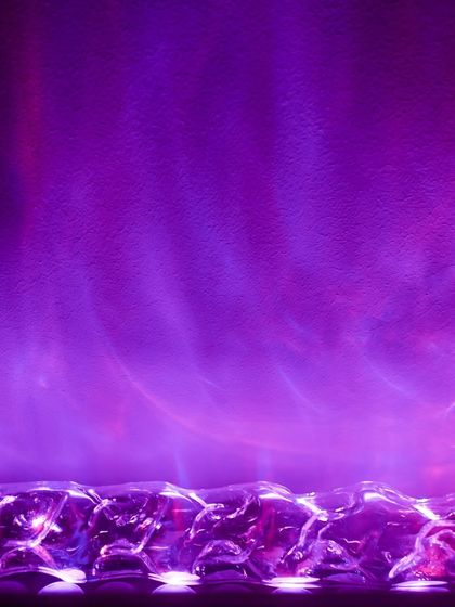 An example of the vibrant, colorful effects achievable with our smart lighting systems. Here, a rich purple light with aurora-like patterns washes up a wall, creating a dynamic and atmospheric mood perfect for entertainment spaces.