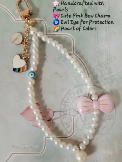 A detailed look at the elements of this custom bag charm. It's handcrafted with pearls, a cute pink bow, a protective evil eye, and a colorful heart, making it a truly unique accessory.