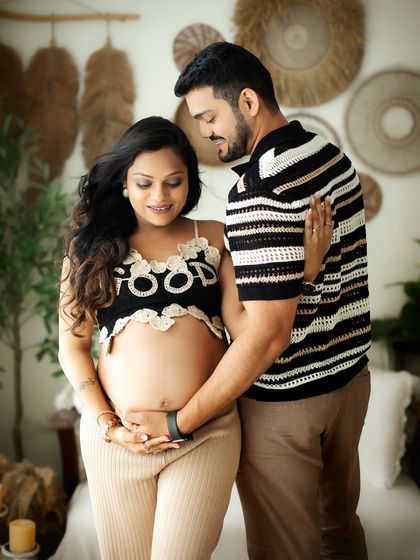 A classic couple pose where the partner stands behind, gently holding the baby bump. It’s a beautiful way to show connection and protection.