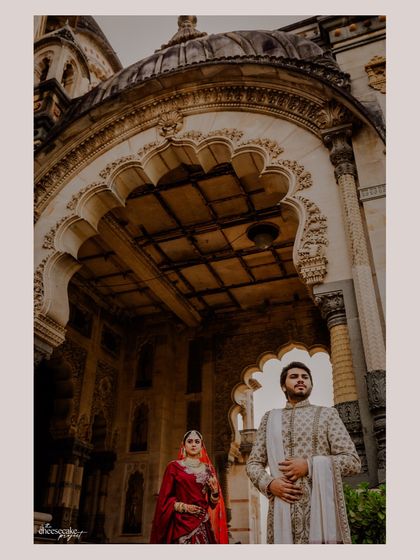 A creative shot looking up at the couple framed by the ornate ceiling of the palace.