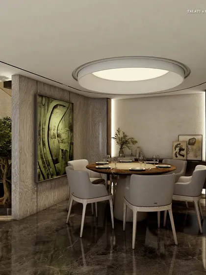 In this minimalist dining nook, a small round table is surrounded by light grey chairs. The space is defined by its clean lines, a large circular ceiling light, and a single piece of abstract art, creating a tranquil spot for intimate meals.