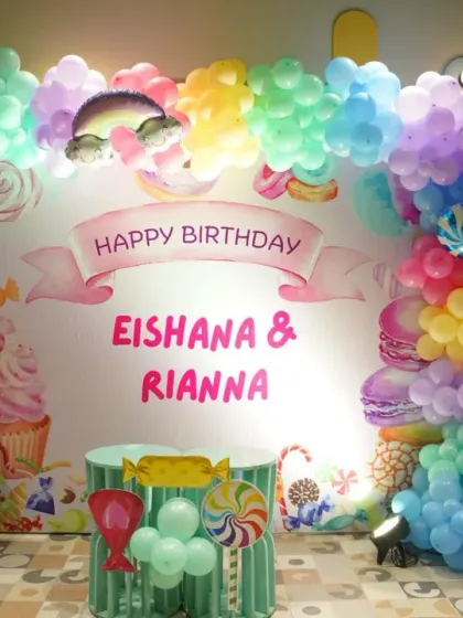 A sweet setup for Eishana and Rianna's birthday. The ice cream and candy-themed backdrop, framed by colorful balloons, is perfect for a joint celebration.