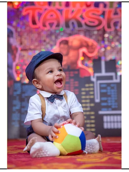A fun and energetic superhero-themed cake smash or first birthday session. The colorful city backdrop and happy expression make for a fantastic memory.