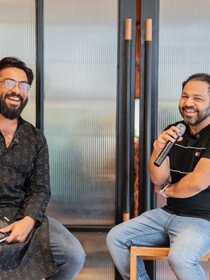Two authors sharing a laugh on stage. We often invite fellow writers to host, fostering a sense of community and peer support.