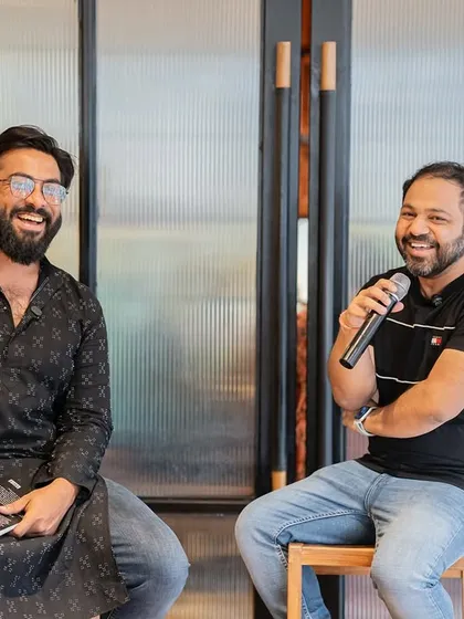 Two authors sharing a laugh on stage. We often invite fellow writers to host, fostering a sense of community and peer support.