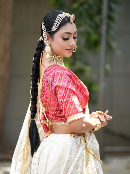 A side profile shot that shows off the elegant braided hairstyle and the beautiful back design of the blouse.