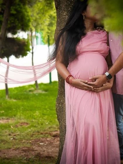 A beautifully framed, intimate moment between an expecting couple in a park. The focus is on their private connection, creating a very personal and emotional photograph.