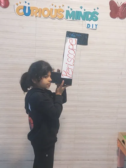 A proud moment with a finished periscope. This project was a great way to learn about optics, and she was thrilled to have a working model that she built herself.