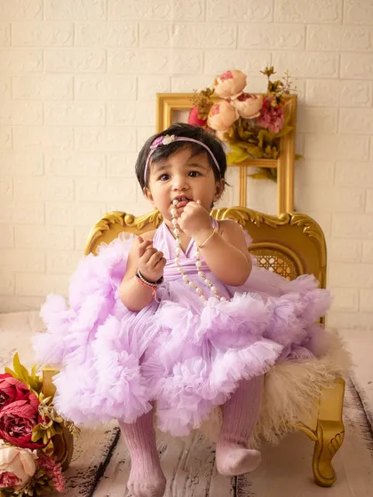 A little princess on her throne. This birthday girl is dressed in a lavender tutu, sitting on a miniature golden chair.