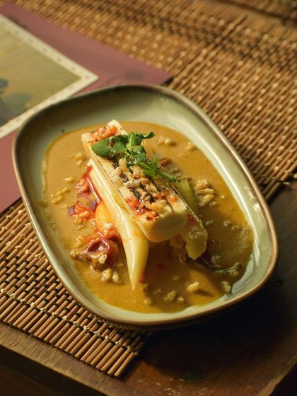 A dish of grilled white asparagus and palm heart in a 'kalchi kodi' turmeric mash, showcasing the chefs' ability to elevate local Goan ingredients.