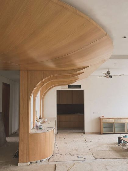 A work-in-progress shot showing the complex carpentry involved in creating a curved, wood-paneled ceiling and wall feature. This shows the skeleton before the final finishes are applied.