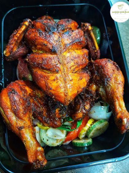 A whole fried chicken, beautifully butterflied and served on a bed of sauteed vegetables.