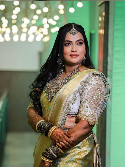 A bride in a stunning lime green and gold Kanjivaram saree. The blouse, with its intricate white and gold embroidery, provides a beautiful contrast, showcasing a unique color combination for bridal wear.