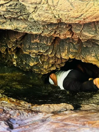 Exploring the tight spaces. A trekker crawling through a narrow passage in the caves.