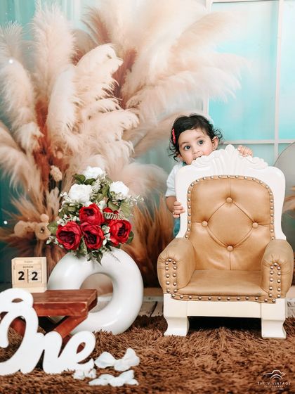 A shy peek from behind a miniature armchair during a first birthday studio shoot. We capture all the facets of your child's personality, from bold to bashful.