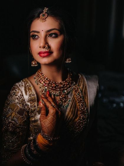 A close-up portrait of the bride, her red lipstick providing a pop of color against her white and gold saree.