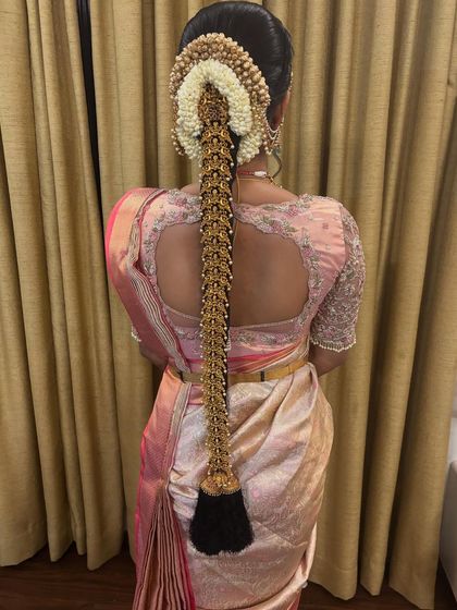 A classic bridal look featuring a full gold 'Jadai' over a neat braid, paired with a beautiful silk saree. This is a timeless choice for any South Indian bride.