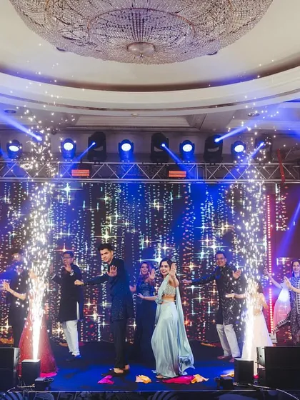 A full-stage family performance with the couple at the center, surrounded by cold pyro, creating a spectacular visual.
