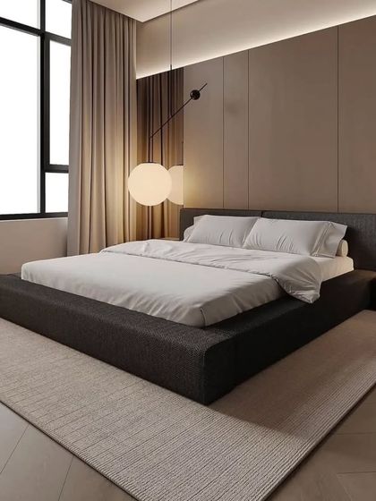 A minimalist bedroom with a low-profile platform bed. The large window and simple color scheme make the room feel spacious and tranquil.